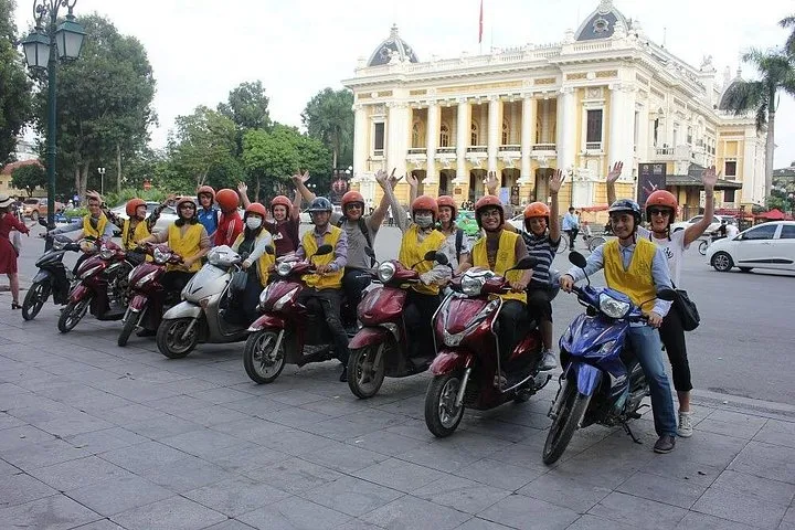 Rider on a Honda scooter parked beside a stall on a Hanoi food tour by motorbike
